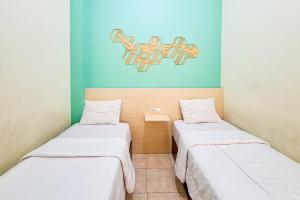 two beds in a room with blue walls at Abbas Syariah Hotel near Menara Kudus Mitra RedDoorz in Kudus +79 photos