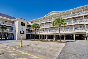 a large building with palm trees in a parking lot at Surf City Stay Motel Unit - Walk to Beach in Surf City