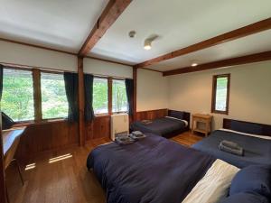 a bedroom with two beds and windows at Cabin D 3min walk Lake Saiko remote work BBQ, 5min drive Kawaguchi Lake Mt Fuji view in Narusawa