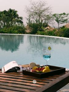 a tray of food and a glass of wine on a table by a pool at Mường Lò Retreat Nghia Lo in Yên Bái