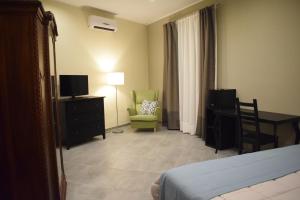 a hotel room with a bed and a chair and a television at Cento Tari' Guest House in Castiglione di Sicilia