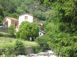 una casa en una colina junto a un río en Chambres d'Hôtes Le Terminus, en Fontan