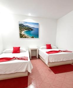 two beds in a room with a painting on the wall at Hotel Zihua Malibu in Zihuatanejo