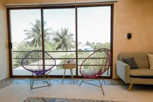 two chairs in a living room with a large window at In Wotoch Chicxulub by Casago in Chicxulub