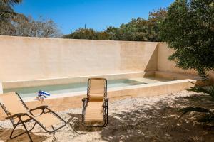 two chairs sitting in front of a swimming pool at In Wotoch Chicxulub by Casago in Chicxulub