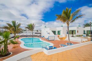 a villa with a swimming pool and palm trees at Apartamentos Sal y Mar in Puerto del Carmen