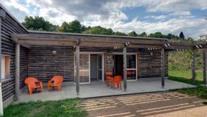 Cabaña de madera con sillas naranjas y patio en Village Vacances Passion Le Cezallier, en Ardes-sur-Couze