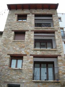 Edificio alto de ladrillo con ventanas y balcón en Valdelinares Apartamentos, en Valdelinares