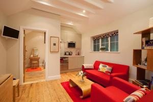 a living room with a red couch and a kitchen at Centre village 2 bedroom cottage - The Byre in Pewsey