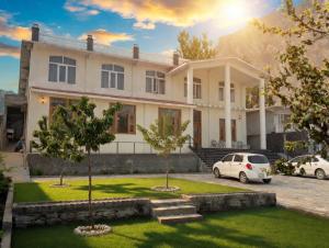 a house with two cars parked in front of it at Hispar Hotel Skardu in Skardu