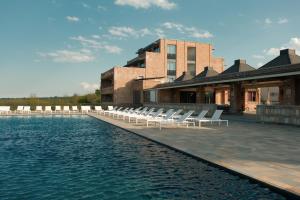 a pool with white lounge chairs next to a building at The Wine Station in Tsinandali