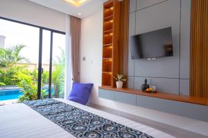 a bedroom with a bed and a tv on a wall at Pondok Uma Jero in Tanah Lot