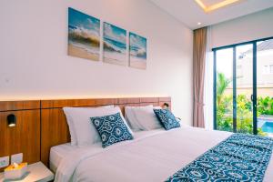 a bedroom with a bed with blue and white pillows at Pondok Uma Jero in Tanah Lot +45 photos