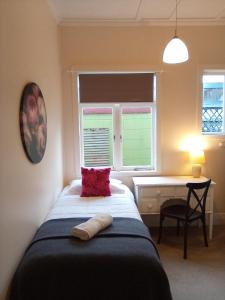 a bedroom with a bed and a desk and a window at School Lane Guesthouse in Whangarei