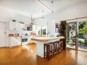 a kitchen with white cabinets and a bar with stools at School Lane Guesthouse in Whangarei