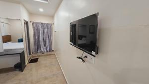 a flat screen tv on a wall in a room at Hotel VAAMANA STAYS in Tirupati