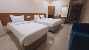 a hotel room with two beds and a blue chair at Hotel VAAMANA STAYS in Tirupati