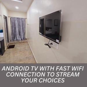 a flat screen tv on a wall in a room at Hotel VAAMANA STAYS in Tirupati