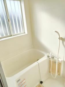 a white bath tub in a bathroom with a window at Sakura Inn in Chiba +10 photos