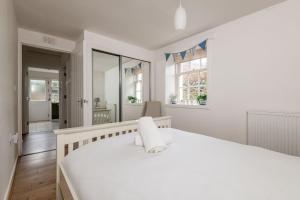 a white bedroom with a large bed and windows at Bangor Cottage - Elie in Elie