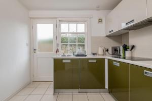 a kitchen with green cabinets and a window at Bangor Cottage - Elie in Elie +15 photos