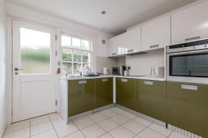 a kitchen with green and white cabinets and a door at Bangor Cottage - Elie in Elie