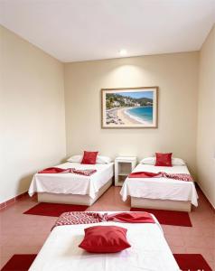 three beds in a room with a beach at Hotel Zihua Malibu in Zihuatanejo