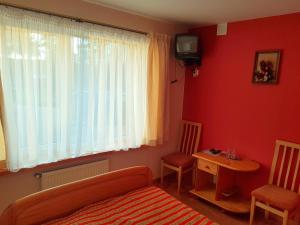 a bedroom with a bed and a table and a television at Piligrimo Užeiga in Kadarės