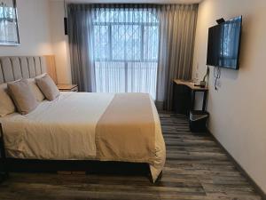 a bedroom with a bed with a television and a window at Hotel 86 Suites in Bogotá