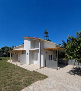 a white building with a tree in front of it at SmallHouseLefkada ΘΕΜΑ in Lefkada