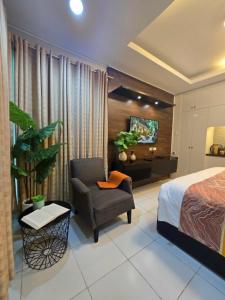 a bedroom with a bed and a chair and a tv at J Spazio Apartelle and Cafe in Baranghauon