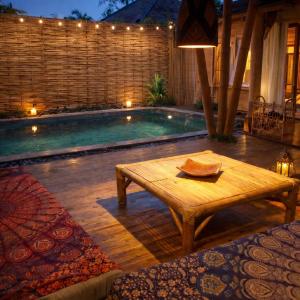 a wooden table sitting next to a swimming pool at Greengo Private POOL VILLA in Gili Meno