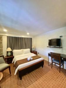 a bedroom with a bed and a desk and a television at Commander Suites de Velada in Antipolo