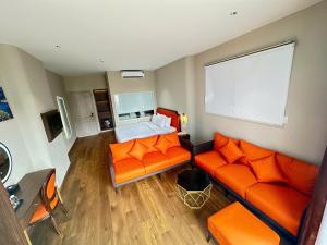 a living room with an orange couch and a bed at Sono Sallute Luxury Hotel in Ho Chi Minh City
