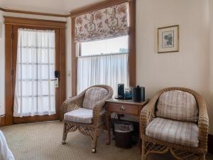 a bedroom with two chairs and a desk and a window at Pacific Grove Inn in Pacific Grove