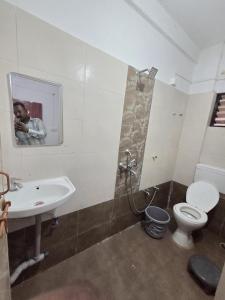 a man taking a picture of a bathroom with a toilet and sink at Hotel Sur Sangam in Nashik