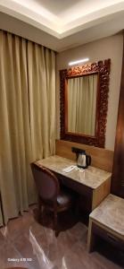 a bathroom with a vanity with a mirror and a chair at Florys Residency in Ooty +4 photos