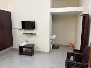 a room with a table and a tv on a wall at Balaas Inn in Karaikal