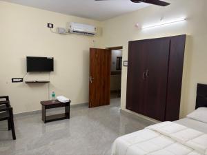 a bedroom with a bed and a tv and a table at Balaas Inn in Karaikal