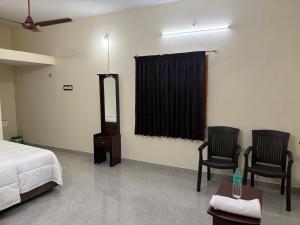 a bedroom with a bed and two chairs and a mirror at Balaas Inn in Karaikal