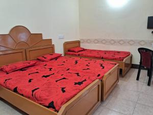 a bedroom with two beds with red comforter at Silver holidays in Yercaud