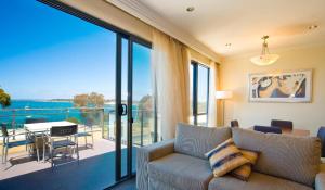 a living room with a couch and a large glass window at Bayside Geelong Hotel & Apartments, an Ascend Collection Hotel in Geelong