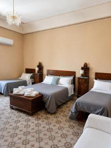 a bedroom with three beds and a chandelier at Alloggio della Posta Vecchia in Agrigento