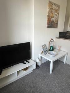 a living room with a flat screen tv and a table at 1 Bed Flat in Weston-super-Mare