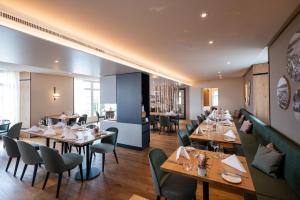 a restaurant with wooden tables and green chairs at See & Park Hotel Feldbach in Steckborn