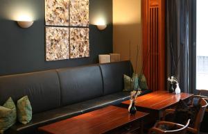 a living room with a black couch and a wooden table at Vienna House by Wyndham Sonne Rostock in Rostock