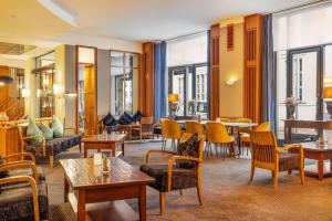 a hotel lobby with tables and chairs and windows at Vienna House by Wyndham Sonne Rostock in Rostock