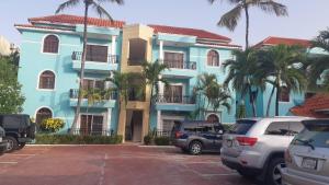 a blue building with cars parked in a parking lot at 2BR Condo with Pool, Walk to Beach, Bvaro in Punta Cana