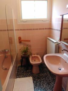 uma casa de banho com um lavatório, um WC e uma janela. em La clairière em Pierrelongue