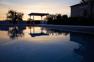 ein leerer Pool bei Sonnenuntergang mit Pavillon in der Unterkunft Hotel Palmensis in Marina Palmense